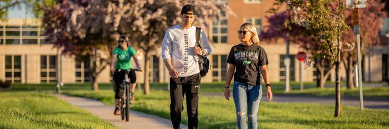 UND student walking along pink cherry blossoms
