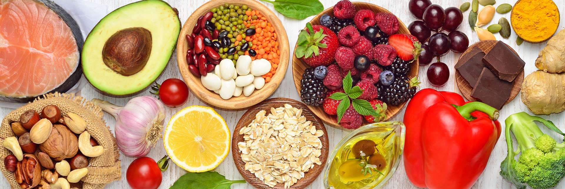 Various bowls and plates of food are pictures: an avocado, beans, legumes, berries, oatmeal, nuts, vegetables