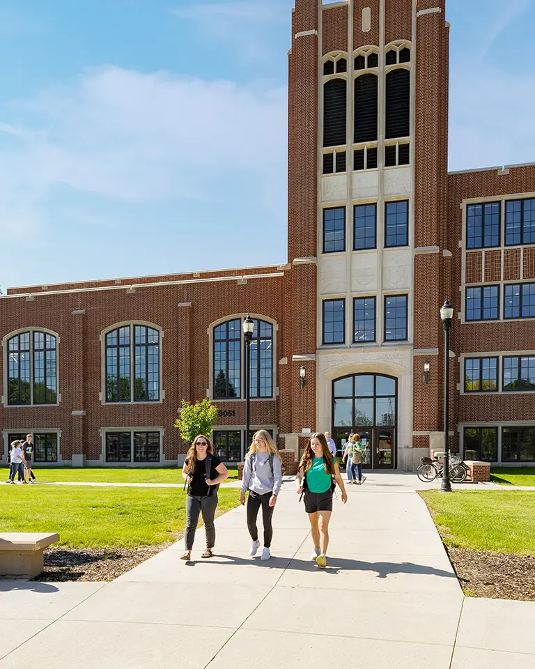 Three students walking in front of library building