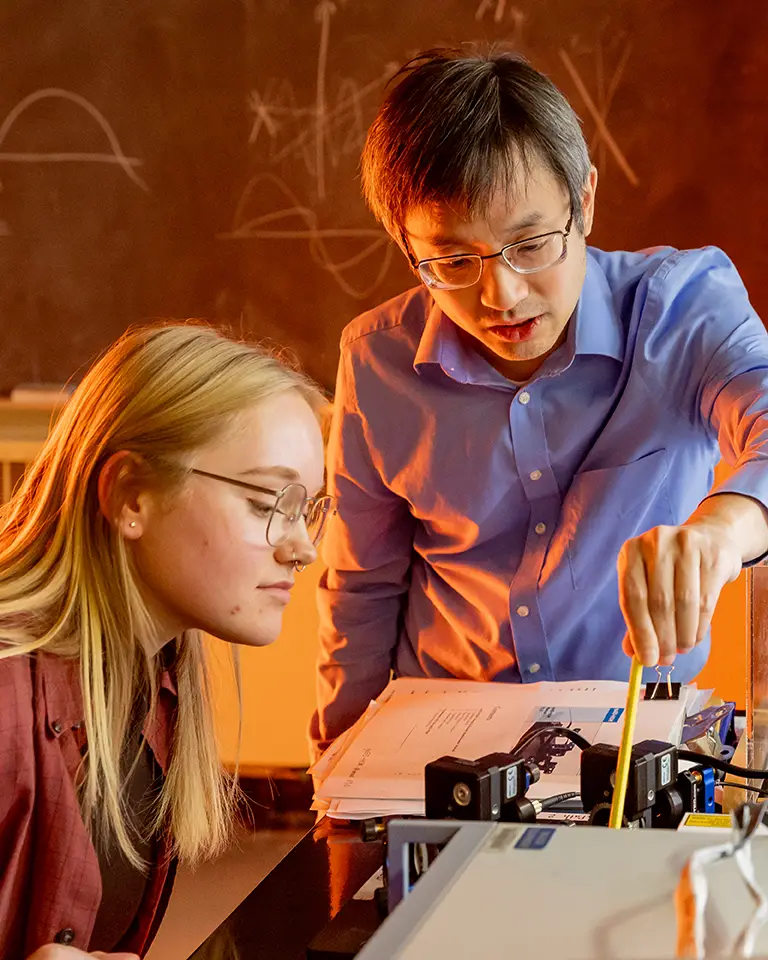 student and professor looking at physics experiment