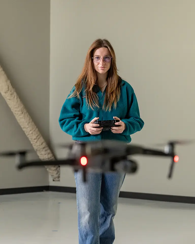 woman with long hair and glasses flying a drone