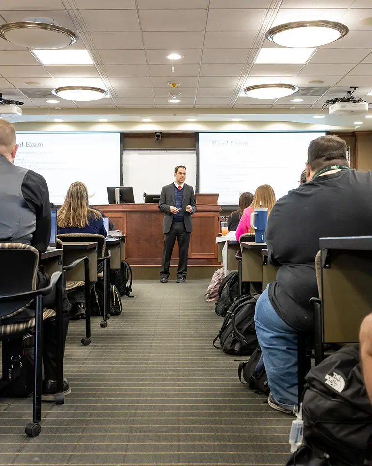 professor at front of class with desks of students on each side