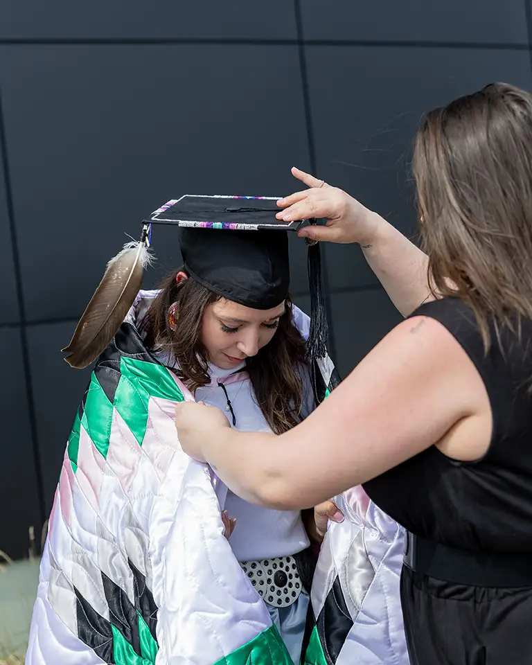 A person is cloaked in a blanket at a commencement ceremony