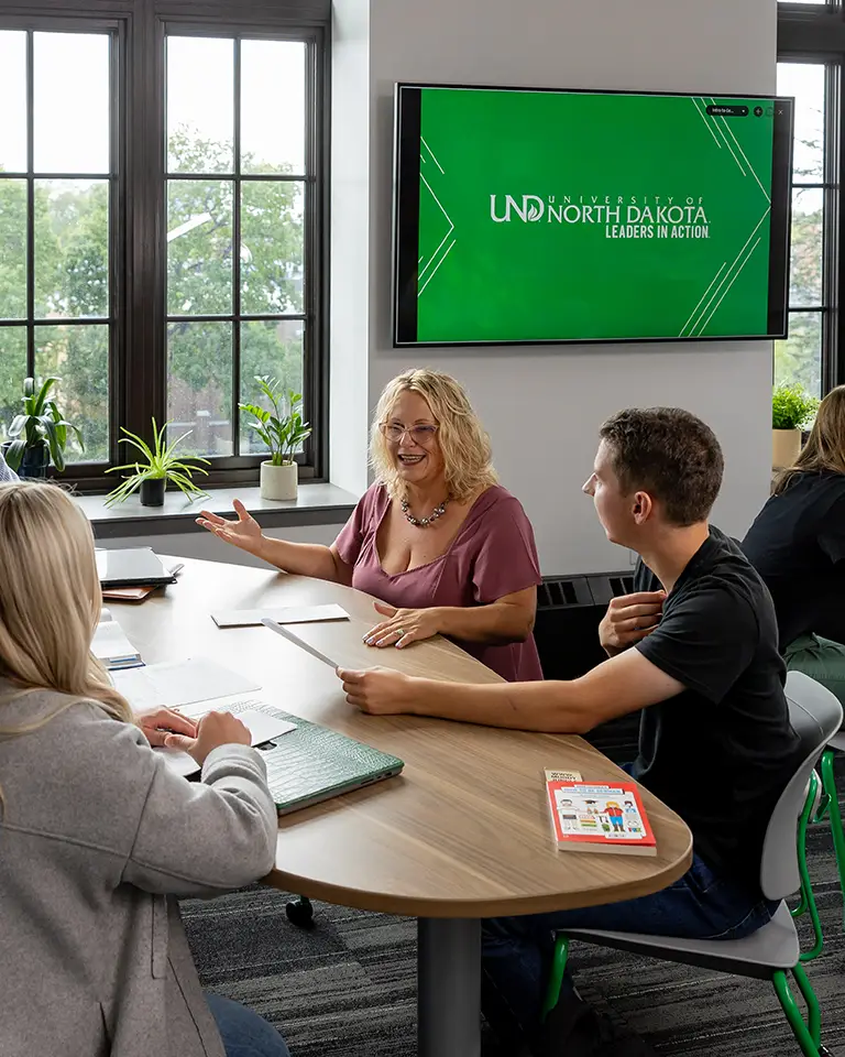 Professors talks to two students at a table.
