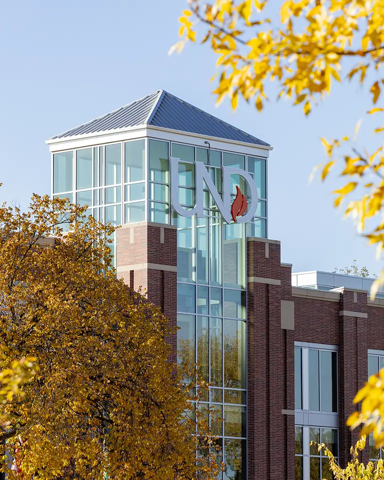 UND logo on the Union appears through fall colored leaves
