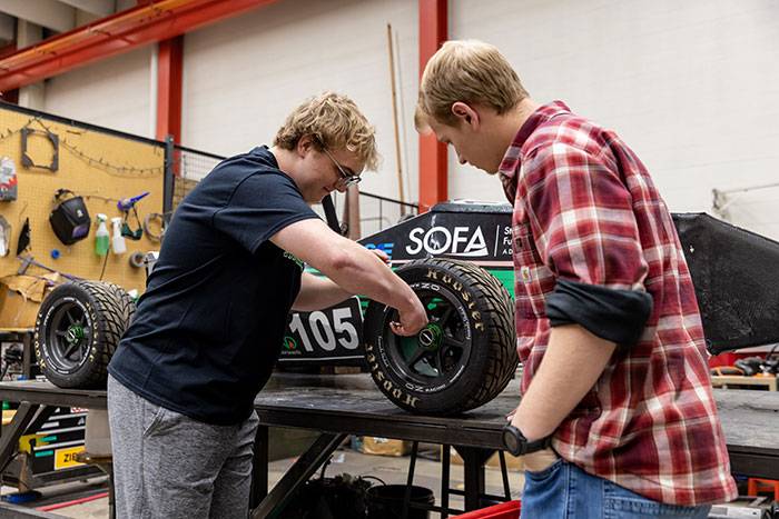 two students working on F1 car