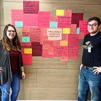 two llc members standing in front of a wall with identities written on pieces of paper