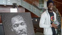 Derrick ssegawa, Vice President of the UND Black Student Association next to Portrait of Martin Luther King, Jr. created by UND student Asha Mohamoud. 