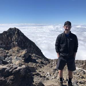UND student standing at top of mountain above the clouds in New Zealand.