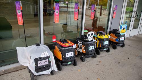 Row of five Kiwi delivery robots are dressed in Halloween Costumes for a contest