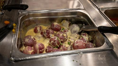 Red potato halves cooked in a cream sauce served in a stainless steel buffet dish
