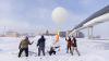 students experiment outside with a weather balloon 
