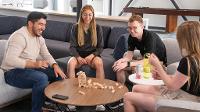 4 young people stack Jenga blocks on a round coffee table