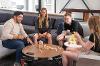 4 young people stack Jenga blocks on a round coffee table