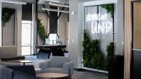 Large study room with air hockey and a large greenery wall with a neon Home At UND sign