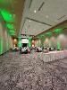 An event space with round tables and chairs. A table for food service sits at the back.
