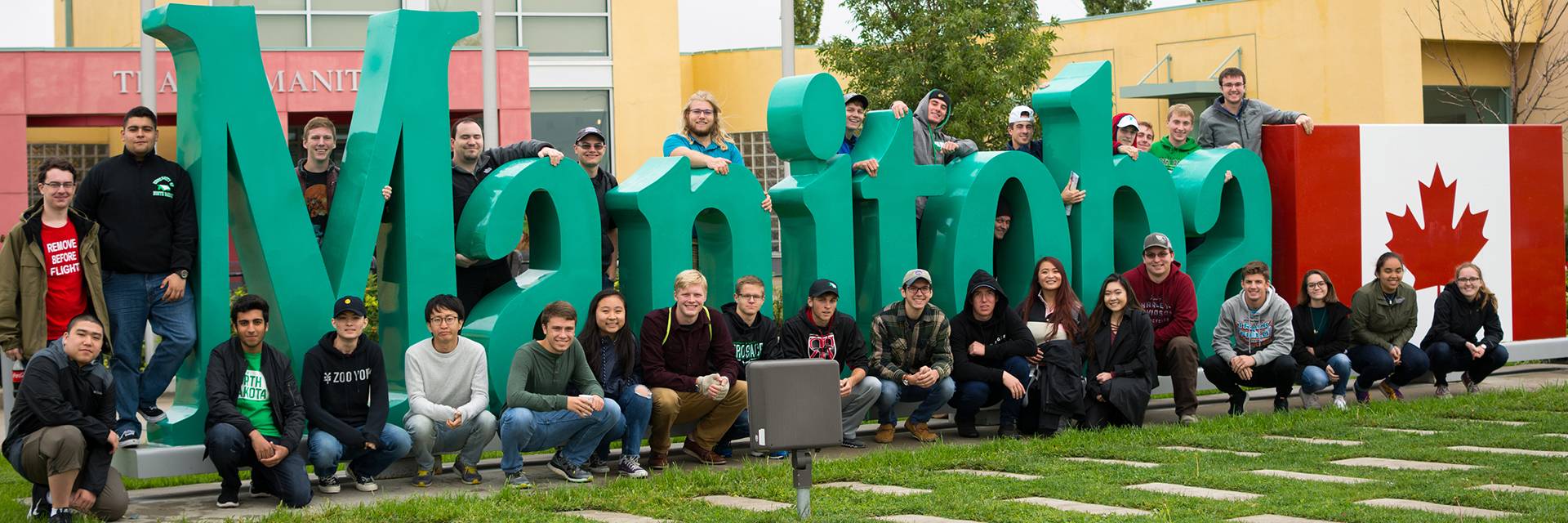 students pose on manitoba sign