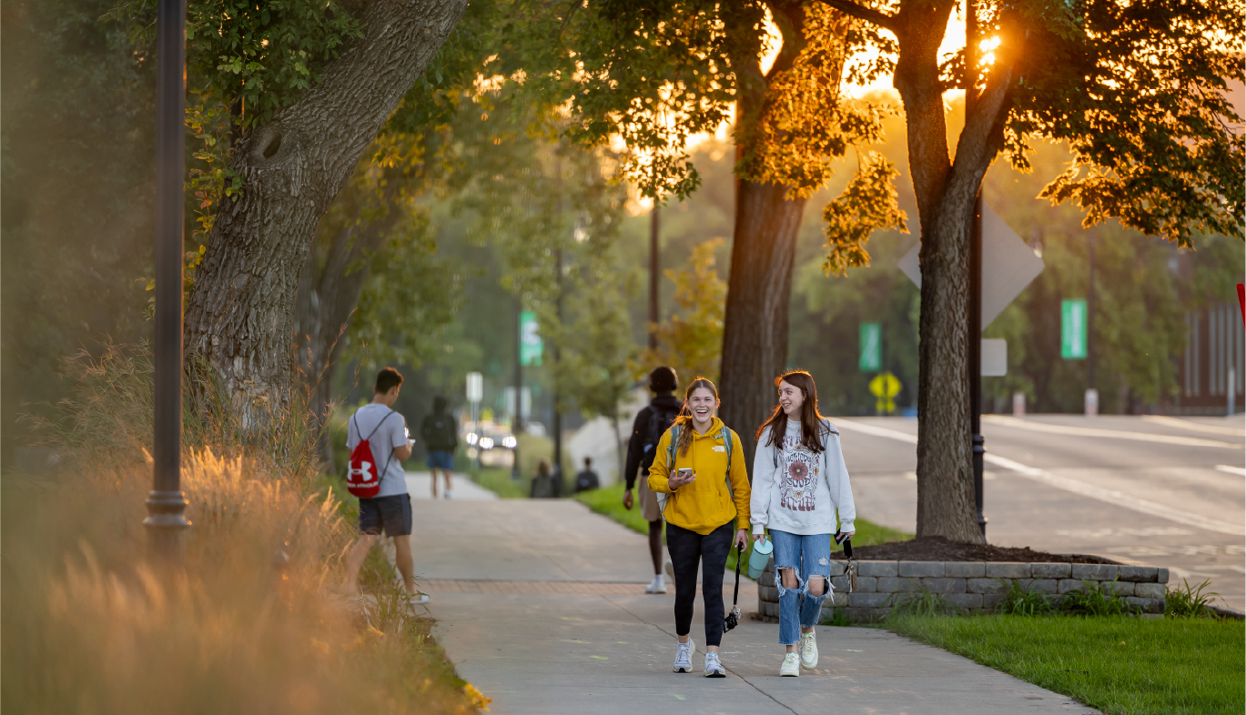 two students walking along University Ave. in the fall at dusk