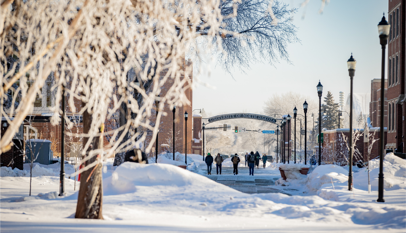 snow blanketing the ground and sidewalks on campus while students walk to class