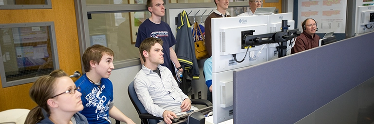 A group of students collaborating at a computer, exploring topics related to their space studies degree