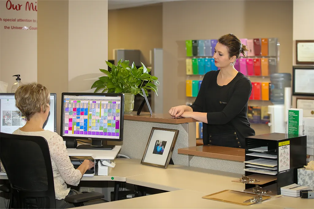 A student checks in with a receptionist at the University Counseling Center front desk.