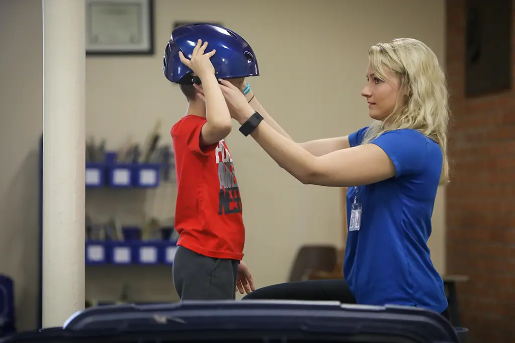 A UND student assists a child with adjusting a bike helmet.