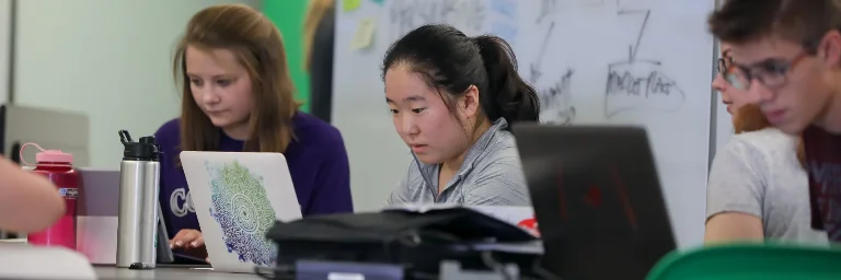 Three data science students deeply focused on analyzing data on their laptop