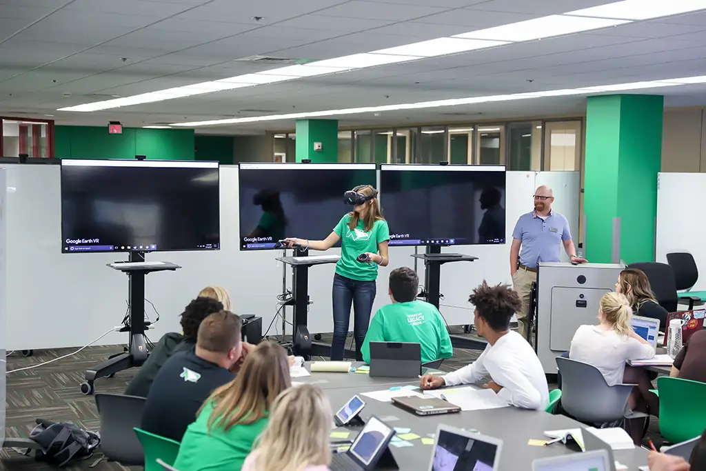 A university instructor using virtual reality to teach complex concepts related to Machine Learning vs AI to students in a modern classroom.