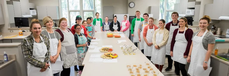 A class full of nutrition students posing for a picture with the nutritious meals they prepared, showcasing their culinary skills and dedication to promoting healthy eating