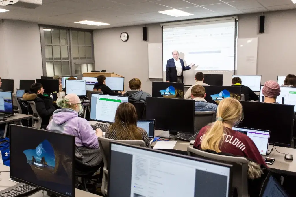 Cyber security students sit in class, attentively listening to their professor as they discuss the latest threats and defense strategies