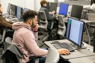 A student of cyber security is using a computer in the classroom.