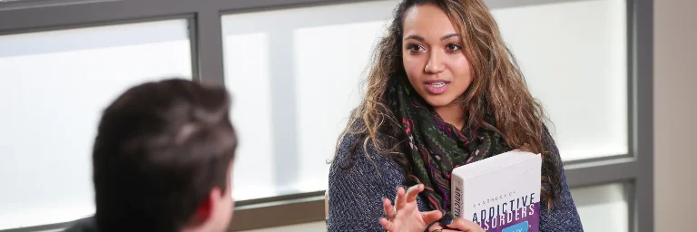 A student with psychology book talking to her professor