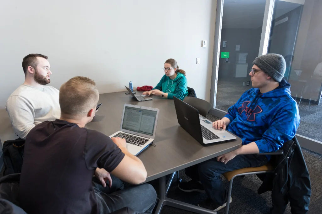 A diverse study group discusses data science and AI, with notes and laptops in view.