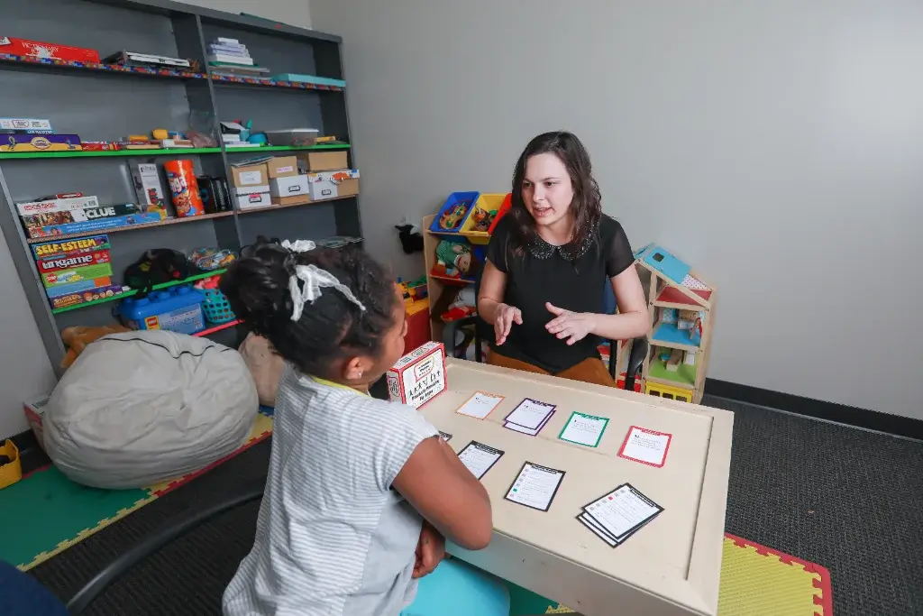 A licensed psychologist working with a child in a therapy room