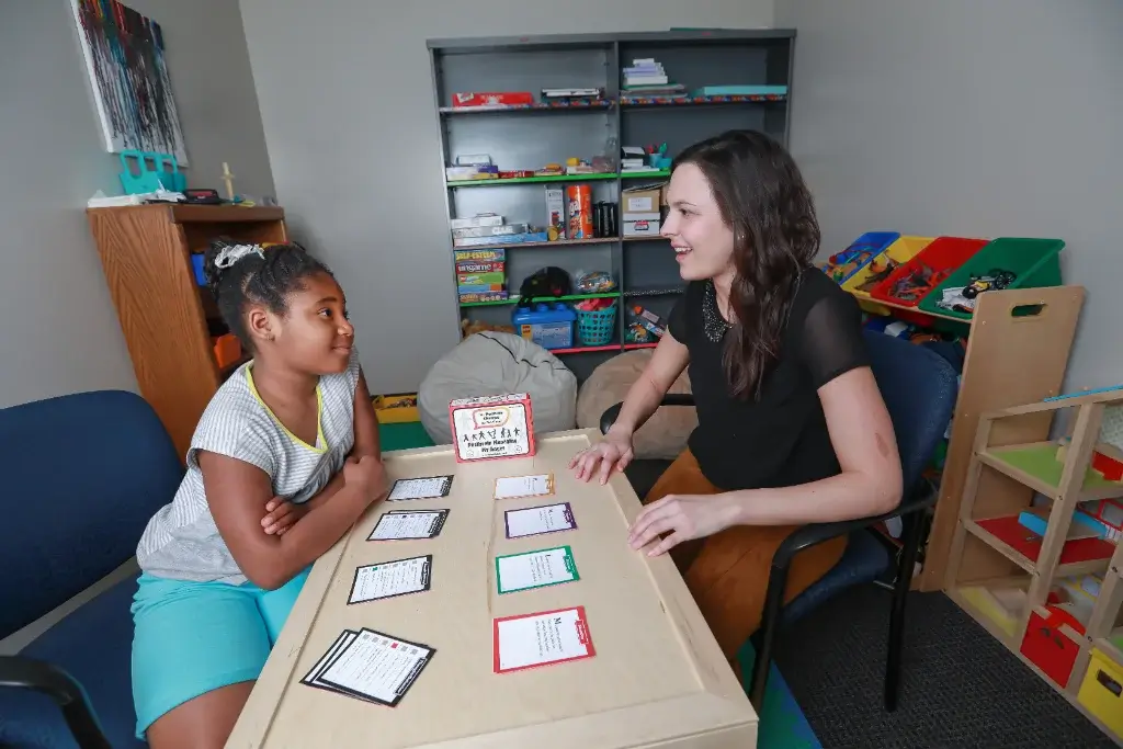 A school psychologist sits with a child, guiding their learning through interactive cards