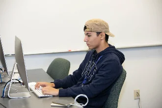 A data science student sits alone in the computer lab, working on his latest project