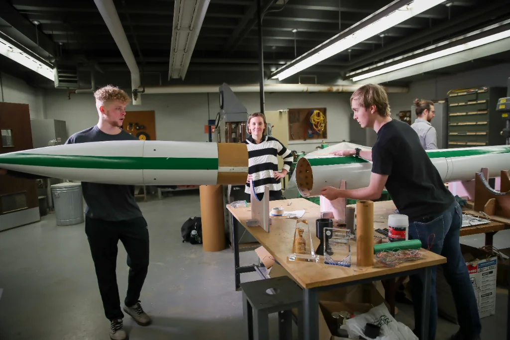 three aerospace engineering students collaborating on a rocket project