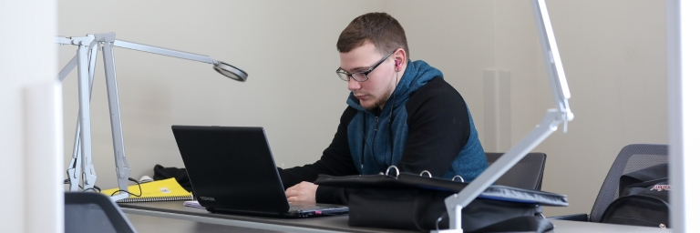 A male student with his laptop on a table