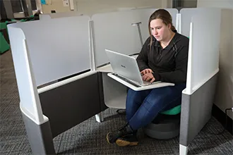 A statistics student is focused on her laptop, carefully studying data with statistical software.