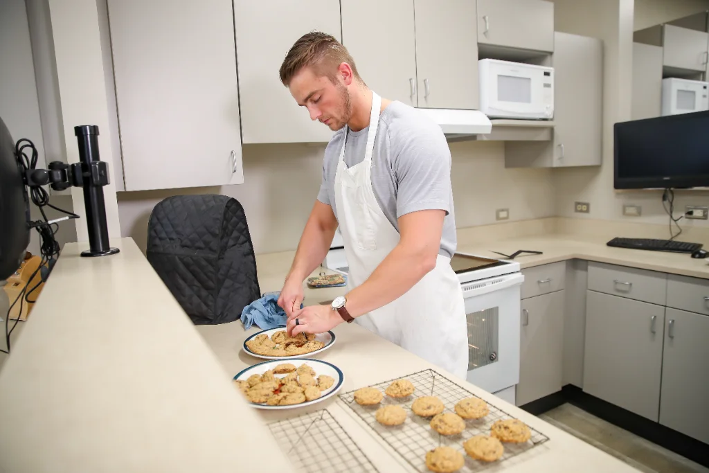 A nutrition student making healthy cookies, carefully selecting ingredients like oats and dark chocolate chips