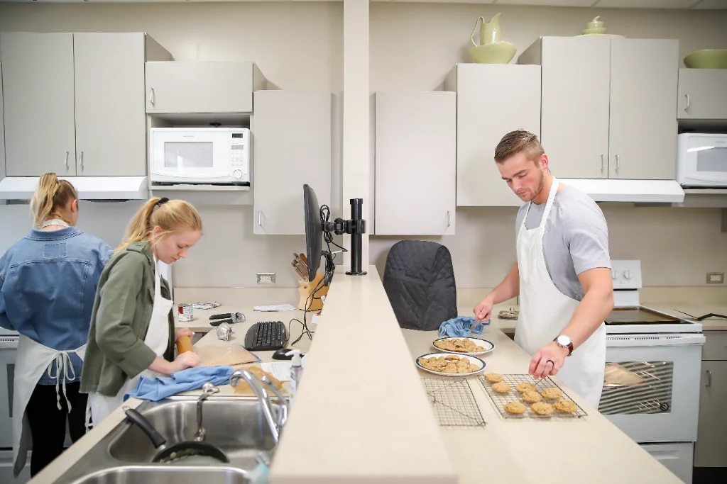 Two nutrition students cooking in kitchen during practical class.