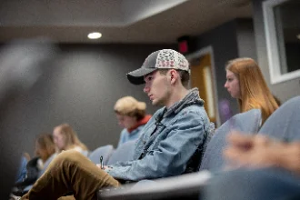 A group of students attentively listening and taking notes in a forensic psychology class