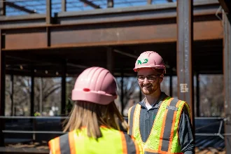 Civil engineering students having a discussion at a construction site.