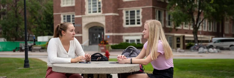 Two female communication students talking on campus.