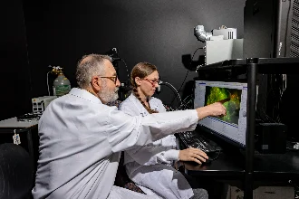 a biomedical student and their teacher stand side by side, focused on a computer screen, engaged in collaborative learning and research