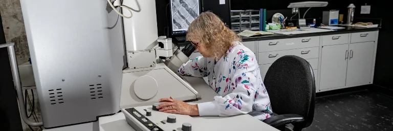 A biomedical engineer examines samples with a microscope in the lab