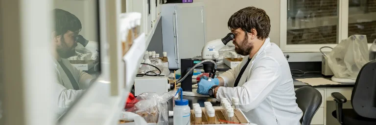 a biomedical engineering student engaged in research, concentrating on their work in a laboratory setting