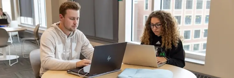 Two students studying with laptops