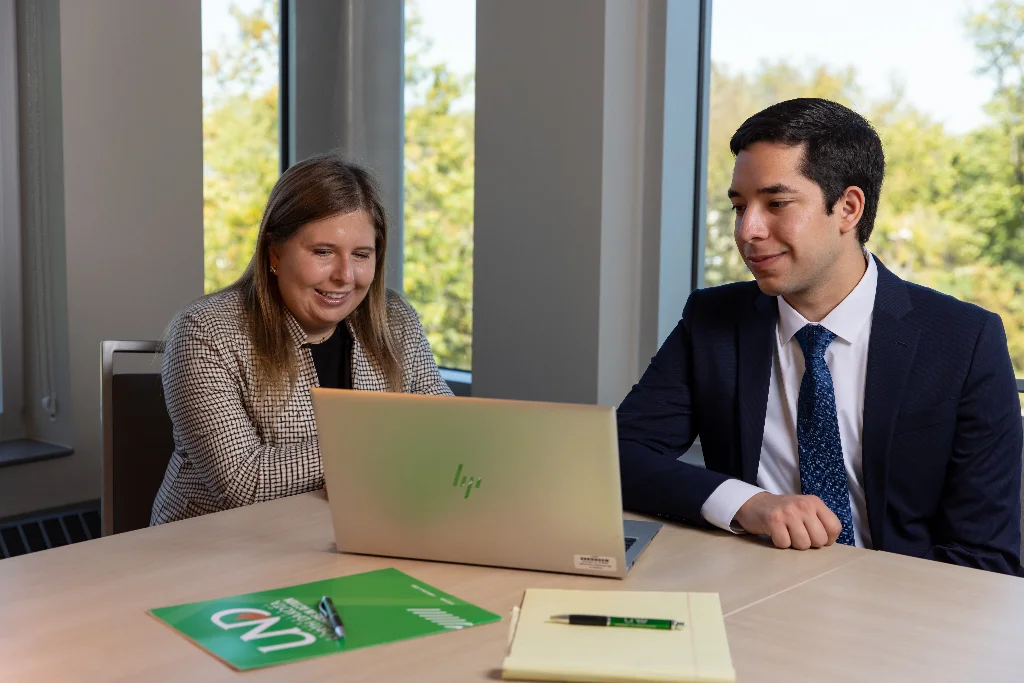 Two accountancy professionals smile as they look at the laptop display