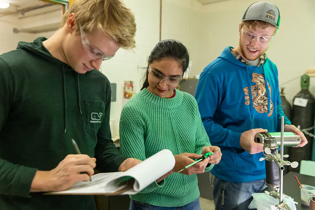 Three geological engineering students collaborating to collect data and perform analysis on a sample in the university's hands on lab.
